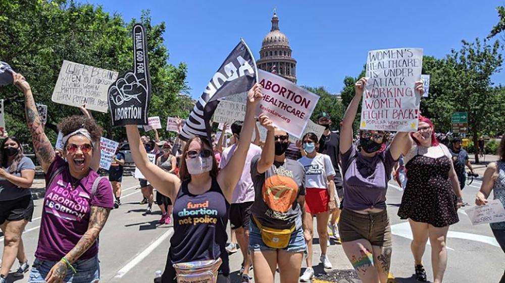 People with signs march in front of the Capitol building in Austin.